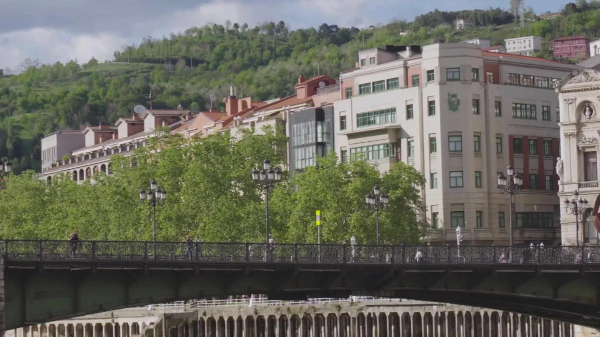 Puente sobre la ría de Bilbao con la ciudad y colinas verdes de fondo