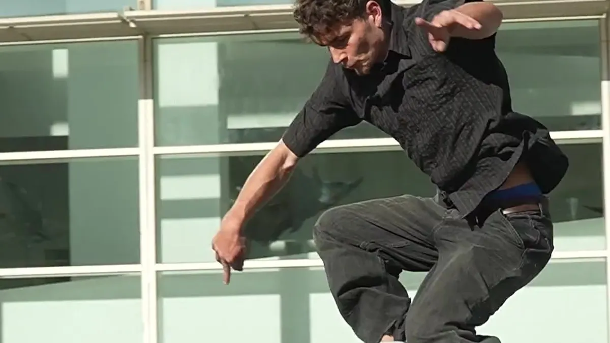 Skater ejecutando un salto frente a una fachada acristalada